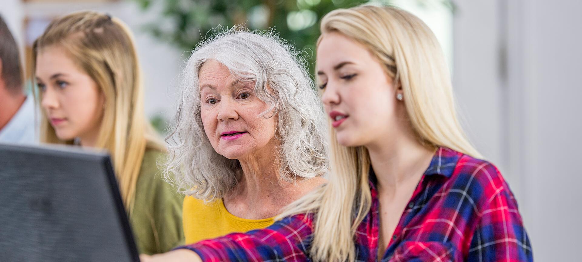 Older woman using a computer with help from a younger woman