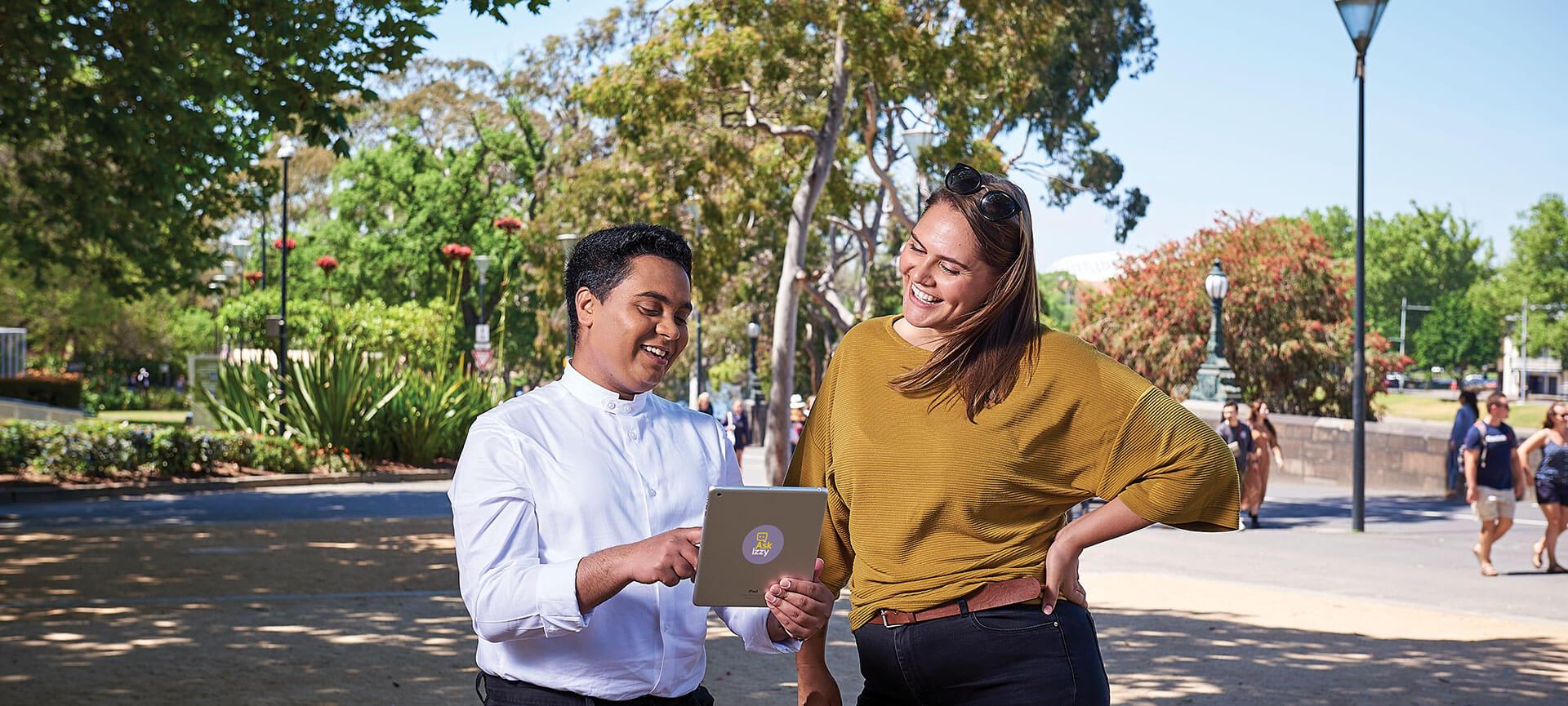 Two people using an iPad with Ask Izzy sticker