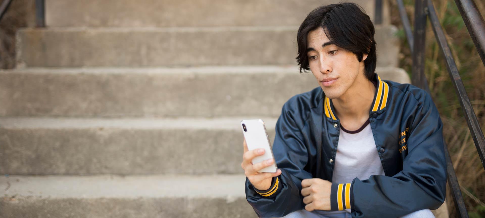 Young man sitting outside looking at phone