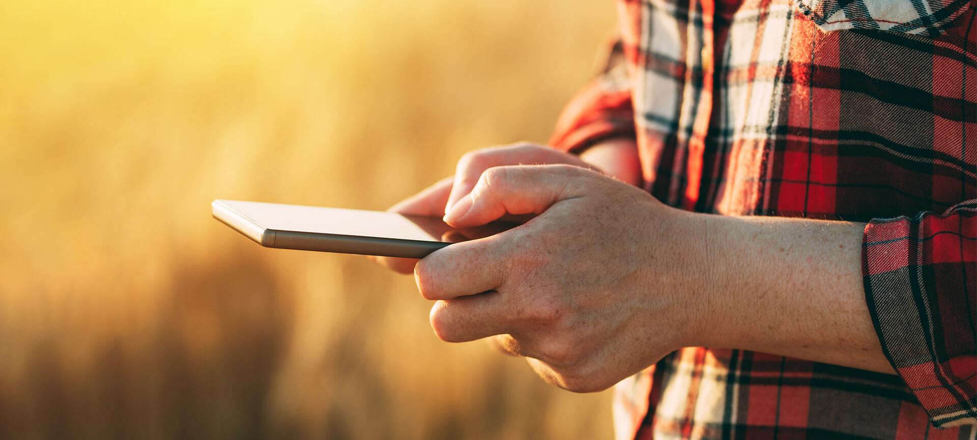 Close up of farmer using phone in a field