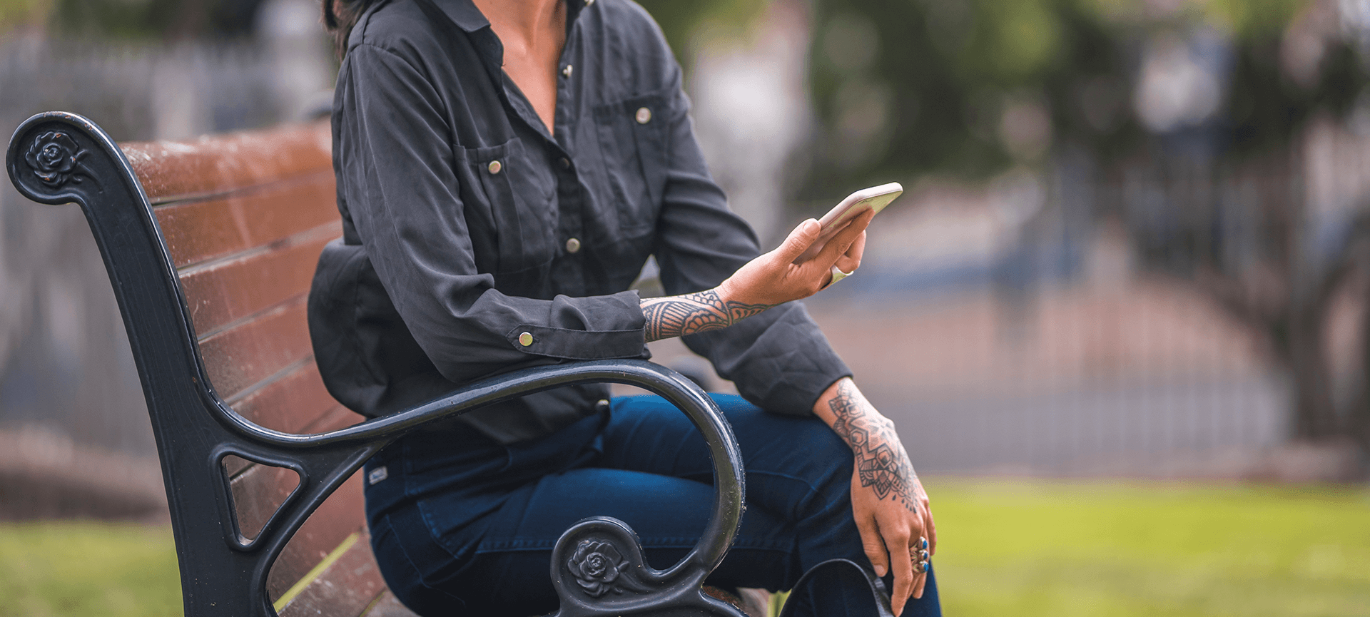 Women sitting on park bench holding phone