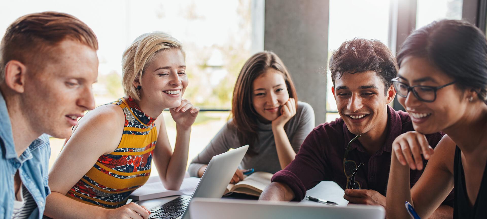 Young people sitting at a table looking at a laptop