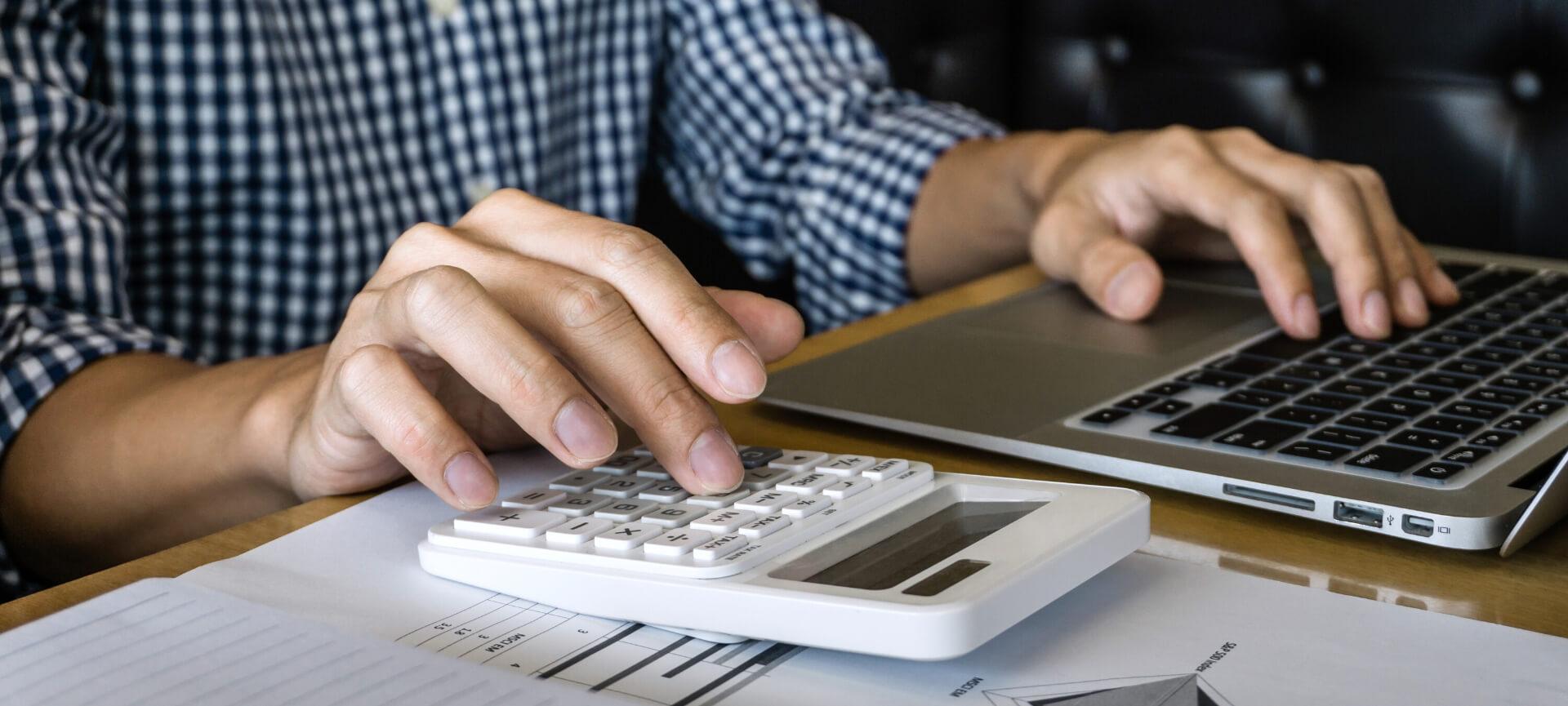 Man using calculator while on laptop