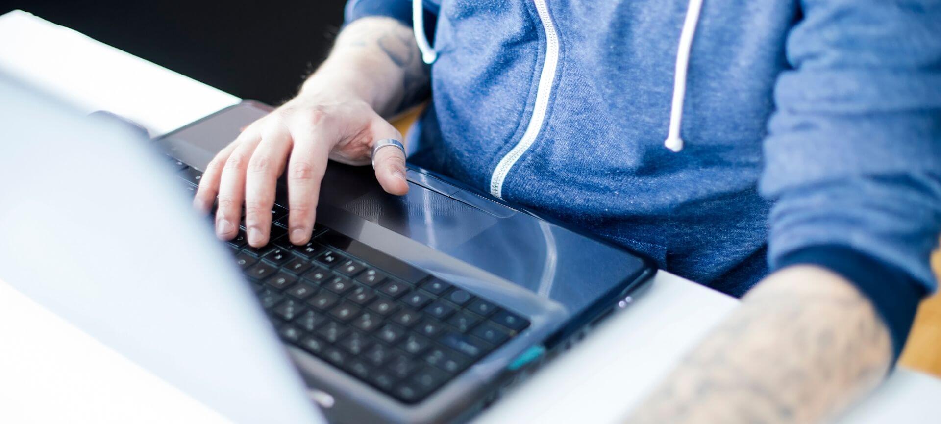 Close up of man in hoodie using laptop