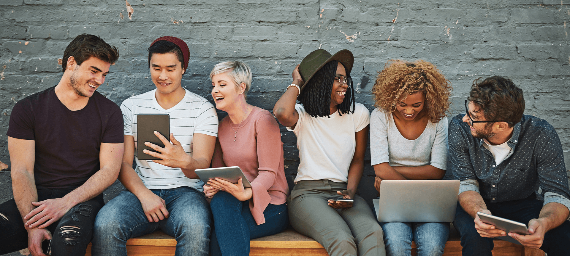 Young people sitting and smiling with devices