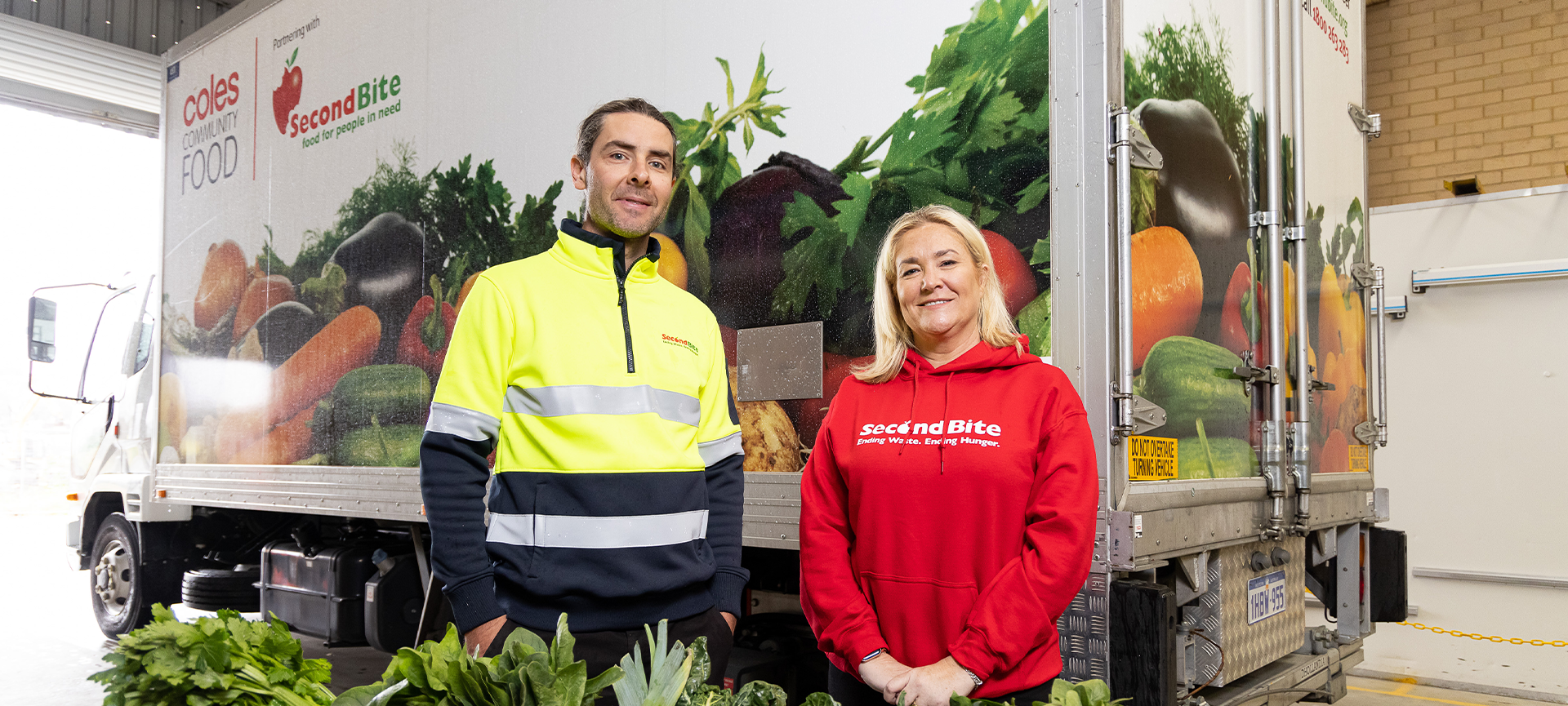 Zoe Fulcher in red jumper standing with Lyndon in high vis in front of the SecondBite truck