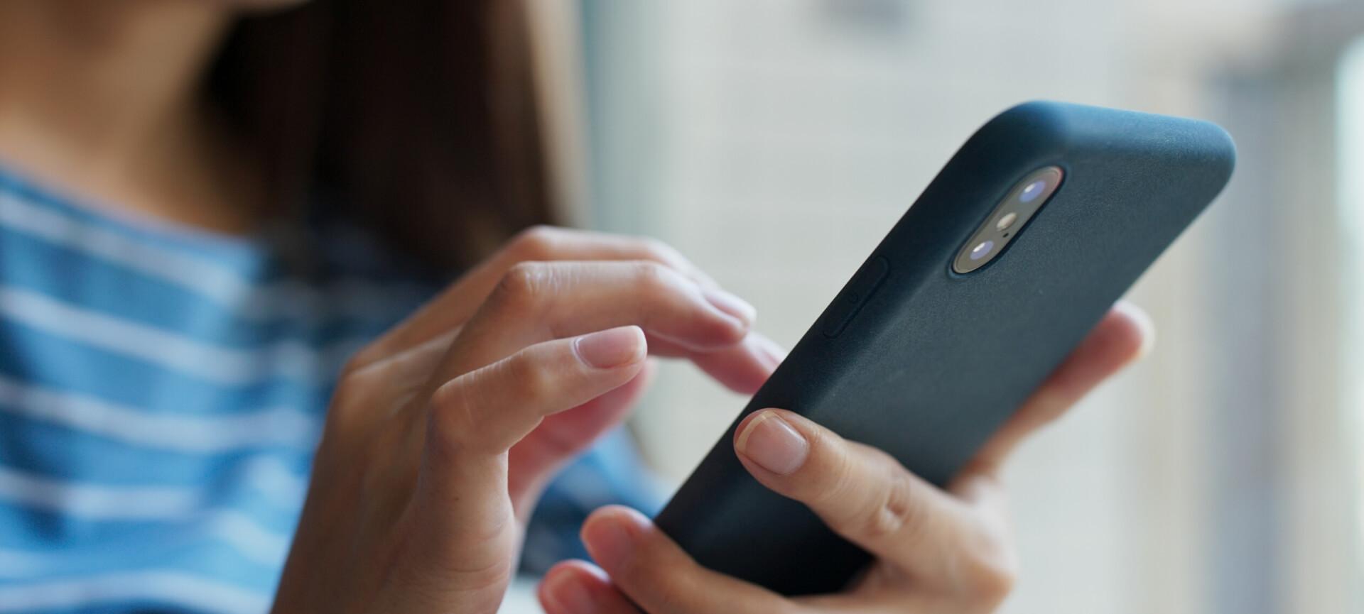 Close up of woman in blue shirt using mobile phone