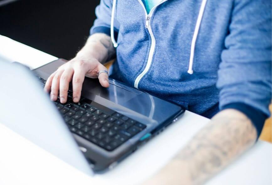 Close up of man in hoodie using laptop