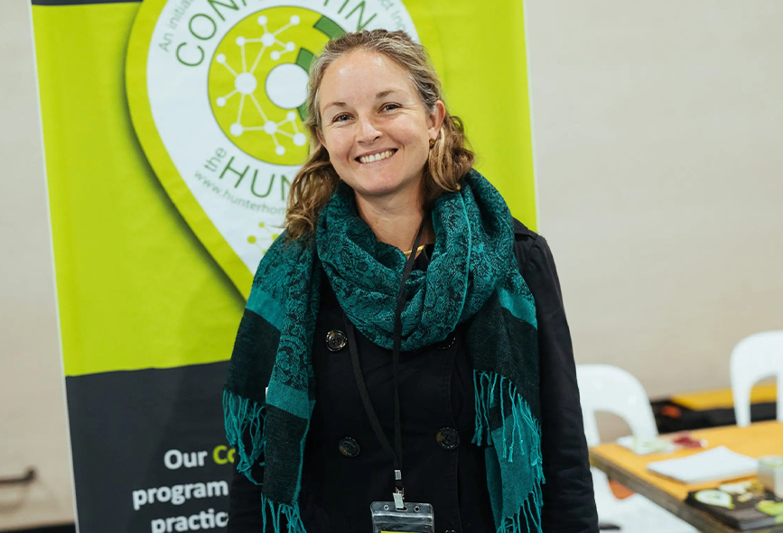 Nissa Phillips standing in front of green Hunter Homeless Connect sign