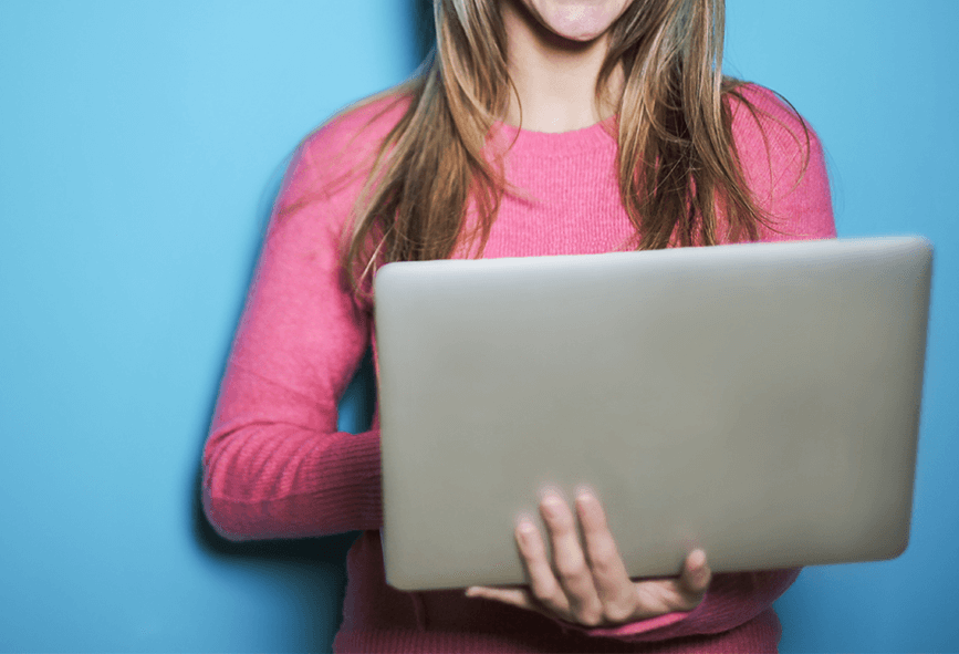 Close up of woman holding laptop with blue background