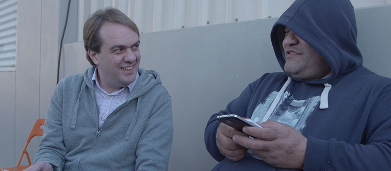 David Spriggs and a friend from Orange Sky looking at Ask Izzy on a phone David Spriggs and a friend from Orange Sky looking at Ask Izzy on a phone