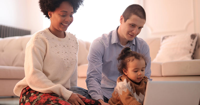 Young family gathered around a laptop computer